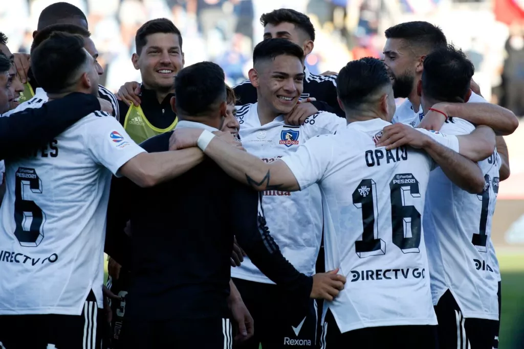 Futbolistas de Colo-Colo se abrazan y sonríen durante un partido en la temporada 2020.