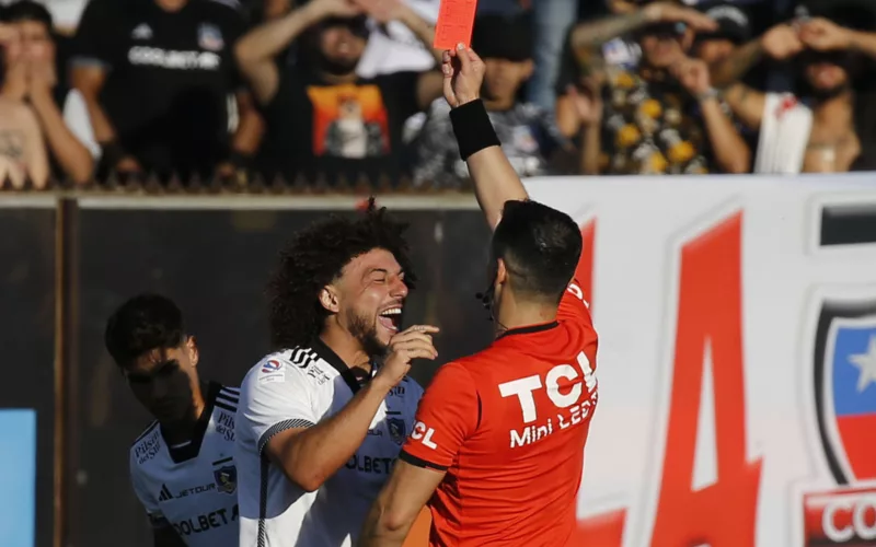Maximiliano Falcón sonriendo mientras el árbitro Fernando Véjar le muestra la tarjeta roja.