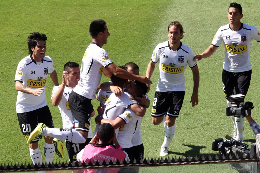 Futbolistas de Colo-Colo durante la temporada 2014 celebrando un gol y se abrazan con evidentes rostros de euforia y felicidad.