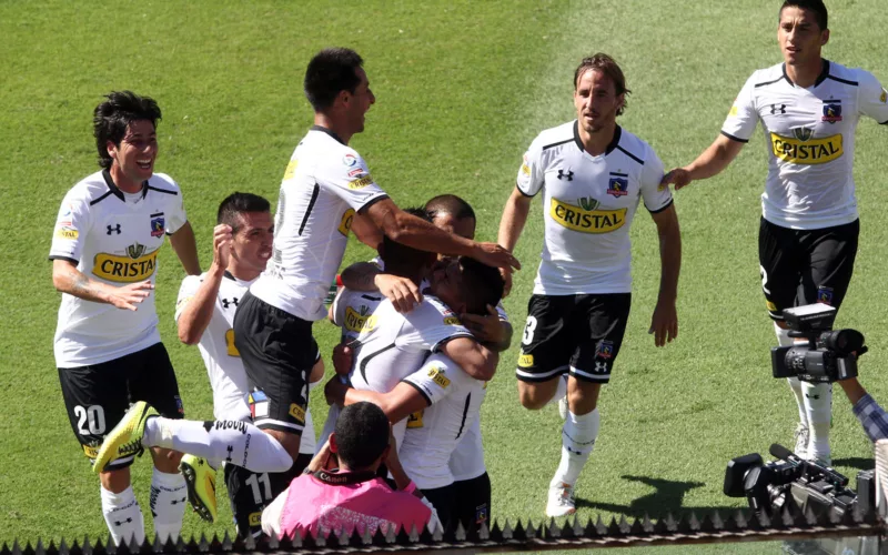 Futbolistas de Colo-Colo durante la temporada 2014 celebrando un gol y se abrazan con evidentes rostros de euforia y felicidad.