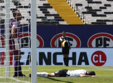 Branco Provoste derramado en el piso en pleno partido con la camiseta de Colo-Colo, mientras que Sebastián Pérez se encuentra parado en el arco norte del Estadio Monumental.