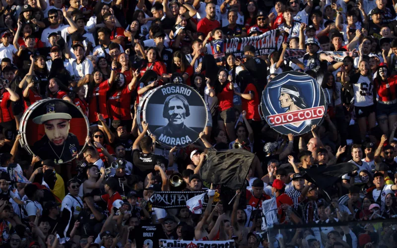 Hinchas de Colo-Colo alientan al equipo y levan tres bombos que representan a la institución durante la temporada 2024.