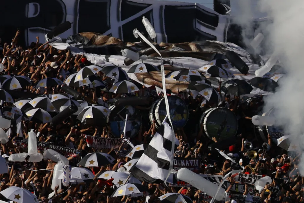 Hinchas de Colo-Colo agolpados en el sector norte del Estadio Monumental, acompañado de bombos y banderas para recibir al equipo.