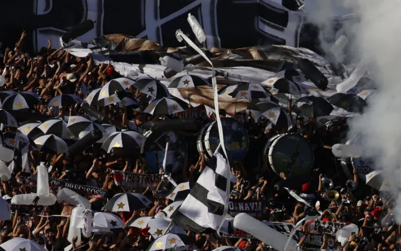 Hinchas de Colo-Colo agolpados en el sector norte del Estadio Monumental, acompañado de bombos y banderas para recibir al equipo.