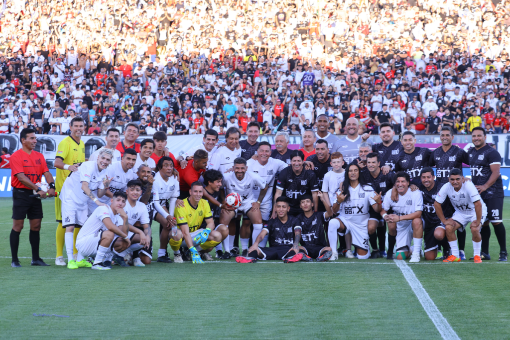 Futbolistas, cantantes y todos los invitados a la despedida de Jaime Valdés posa con el fondo del sector cordillera repleto de hinchas de Colo-Colo en el Estadio Monumental.