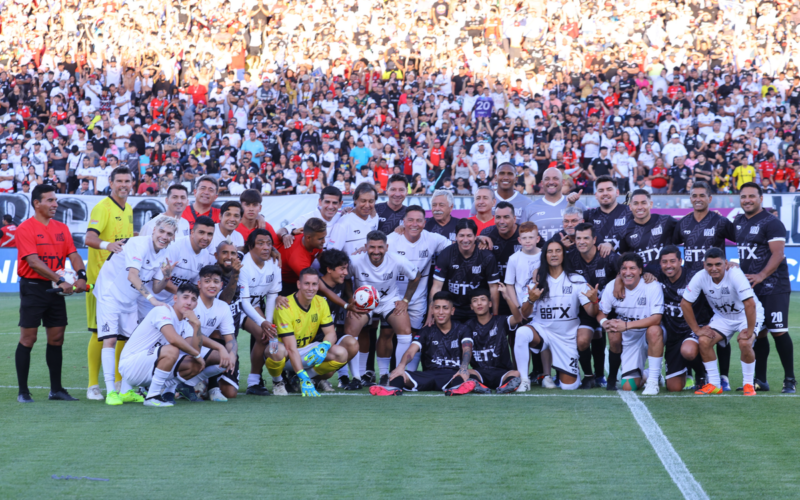 Futbolistas, cantantes y todos los invitados a la despedida de Jaime Valdés posa con el fondo del sector cordillera repleto de hinchas de Colo-Colo en el Estadio Monumental.