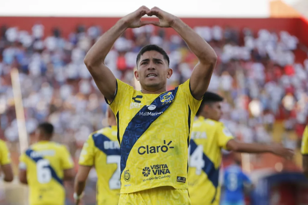 Primer plano a Braian Martínez celebrando su gol contra Universidad Católica en el Estadio Santa Laura, haciendo un corazón con sus manos.