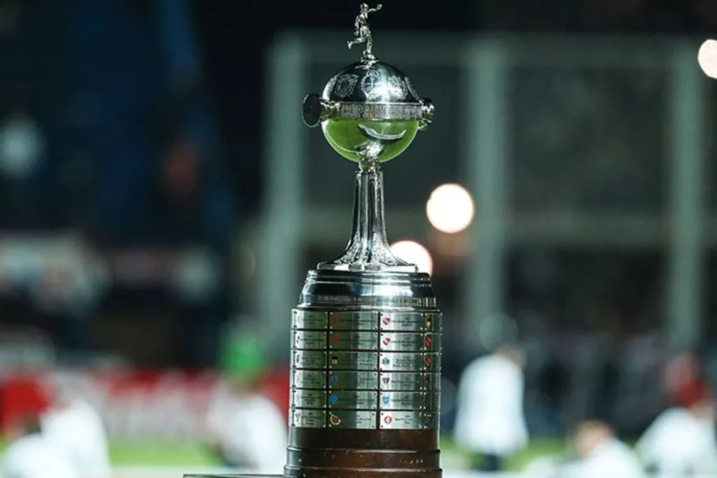 Primer plano al trofeo de la Copa Libertadores en el borde de una cancha.