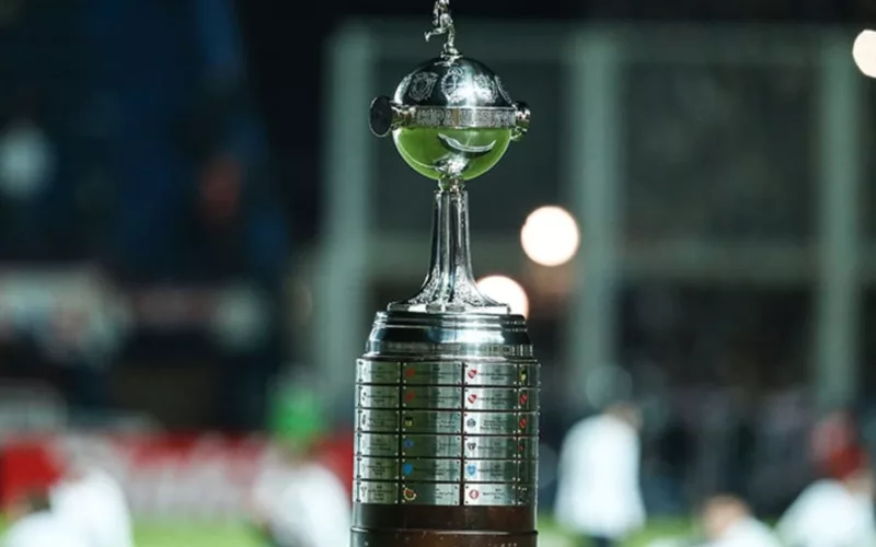 Primer plano al trofeo de la Copa Libertadores en el borde de una cancha.