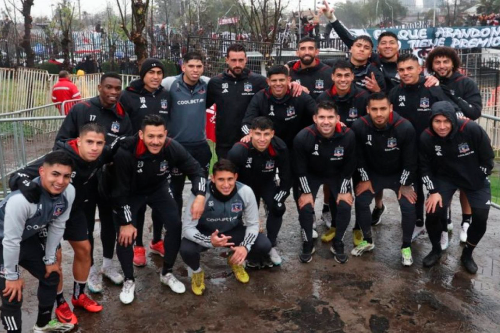 Plantel de Colo-Colo 2023 posa ante las cámaras y de fondo se ven los hinchas de Colo-Colo en un nuevo arengazo desde las afueras del Estadio Monumental.