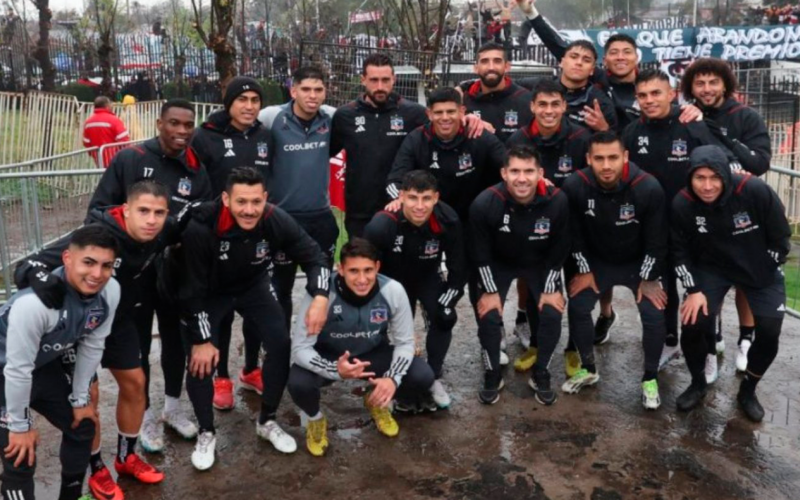 Plantel de Colo-Colo 2023 posa ante las cámaras y de fondo se ven los hinchas de Colo-Colo en un nuevo arengazo desde las afueras del Estadio Monumental.