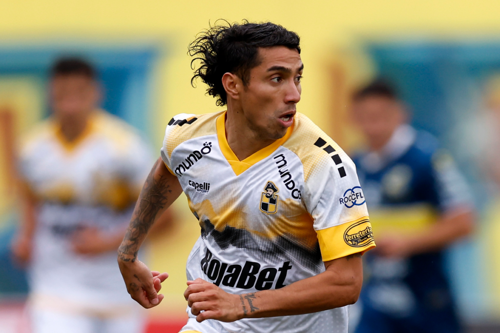Luciano Cabral defendiendo la camiseta de Coquimbo Unido durante la temporada 2024. Tiene la mirada puesta en un objetivo que observa de reojo.