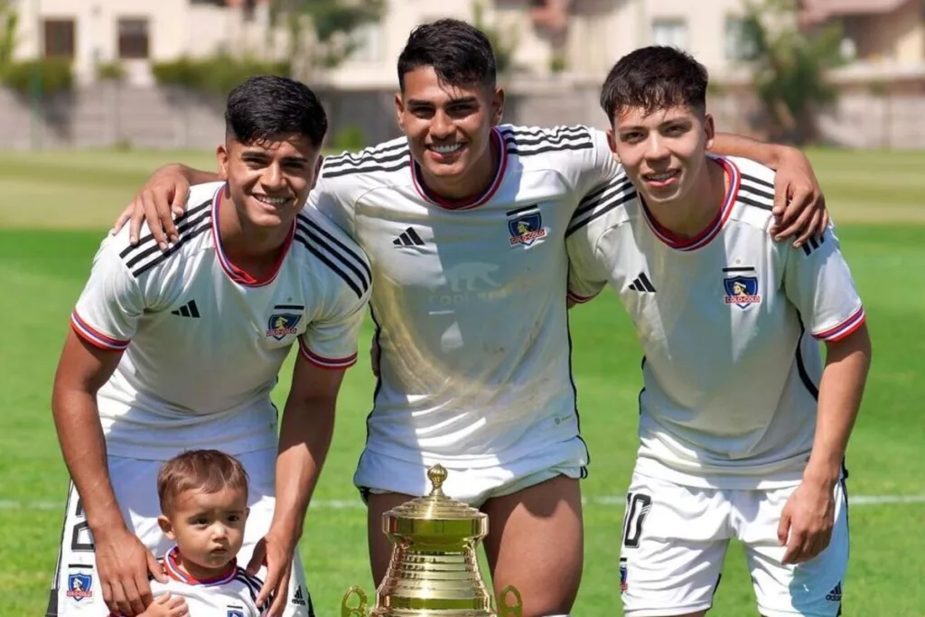 Jugadores de Colo-Colo Proyección sonriendo junto a un trofeo.