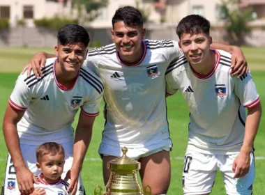 Jugadores de Colo-Colo Proyección sonriendo junto a un trofeo.