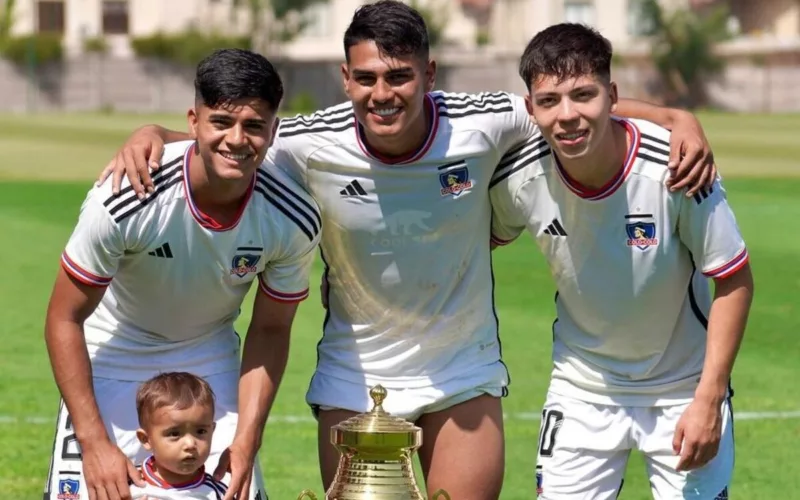 Jugadores de Colo-Colo Proyección sonriendo junto a un trofeo.
