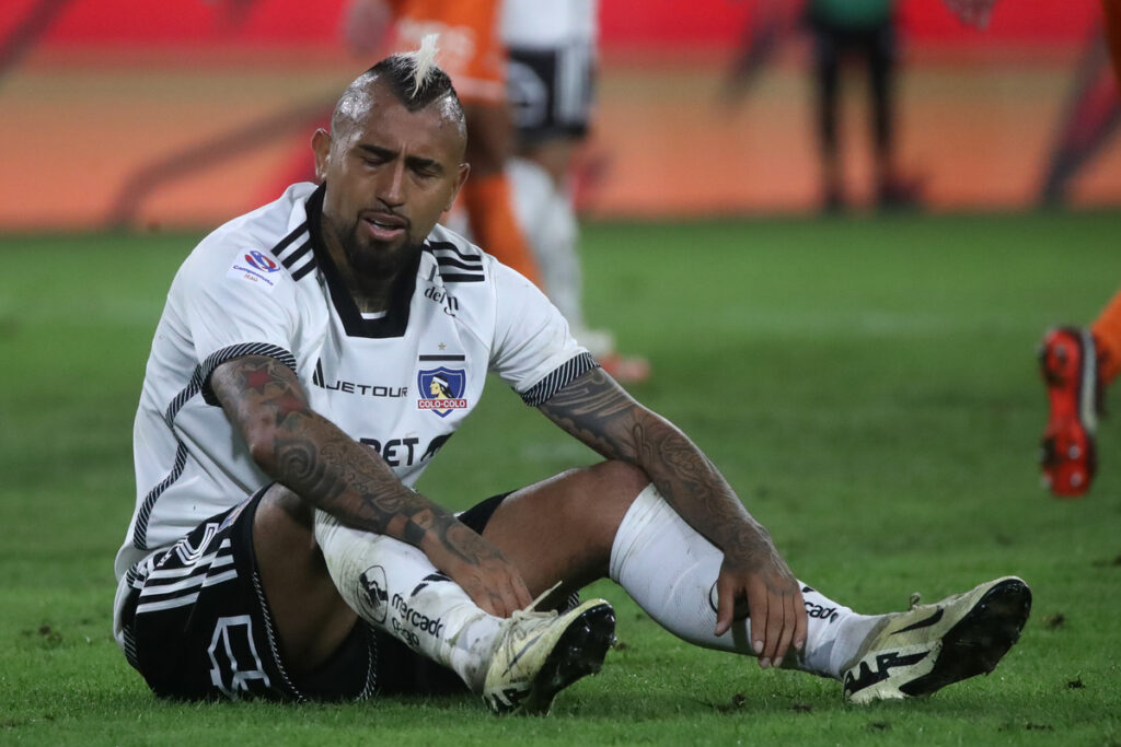 Arturo Vidal sentado sobre el césped de la cancha principal del Estadio Monumental.