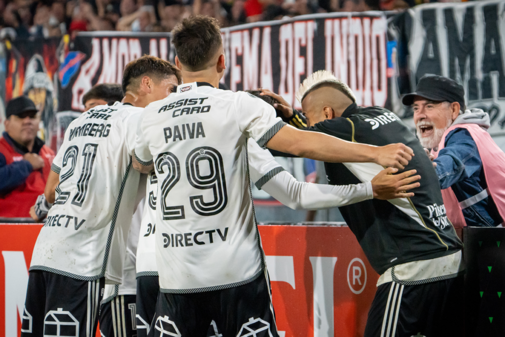 Futbolistas de Colo-Colo se abrazan y celebran un gol al borde del campo del Estadio Monumental durante la Copa Libertadores 2024.