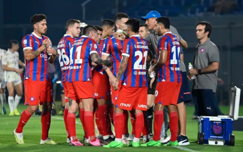 Futbolistas de Cerro Porteño se reúnen al borde del terreno de juego para recibir una instrucción de su director técnico.