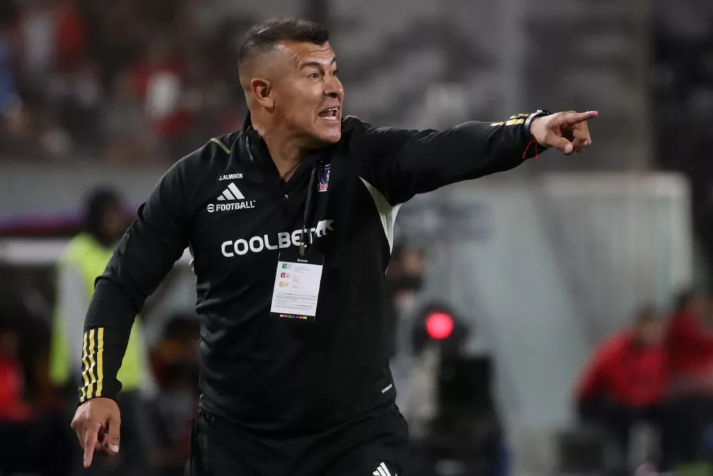 Jorge Almirón reparte una instrucción con su brazo izquierdo apuntando a un objetivo en pleno partido dirigiendo a Colo-Colo.