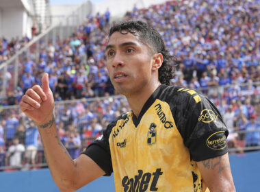 Luciano Cabral levanta su pulgar en pleno partido con l camiseta de Coquimbo Unido y la hinchada de Universidad de Chile de fondo.