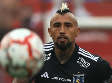 Arturo Vidal en pleno partido con la camiseta de Colo-Colo con la mirada fija puesto en un balón que va por los aires.