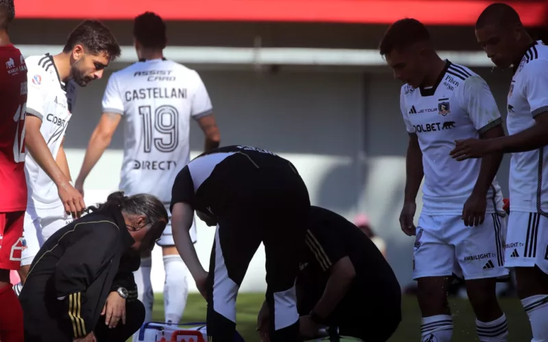 Jugadores de Colo-Colo mientras atendían a un futbolista en el campo de juego.