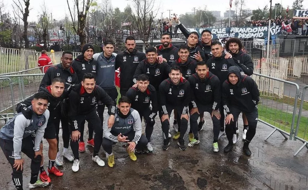 Plantel de Colo-Colo posa ante las cámaras con la hinchada de fondo en la entrada de vehículos del Estadio Monumental en un Arengazo.