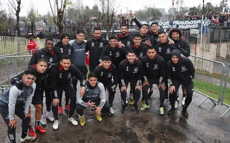 Plantel de Colo-Colo posa ante las cámaras con la hinchada de fondo en la entrada de vehículos del Estadio Monumental en un Arengazo.