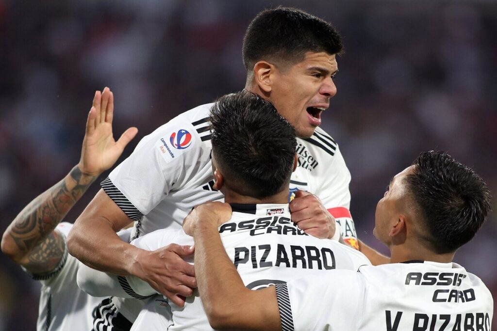 Jugadores de Colo-Colo abrazados celebrando un gol.