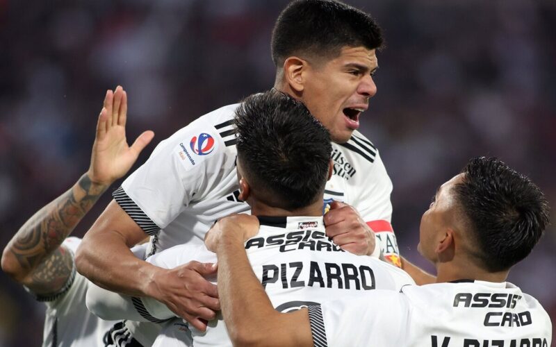 Jugadores de Colo-Colo abrazados celebrando un gol.