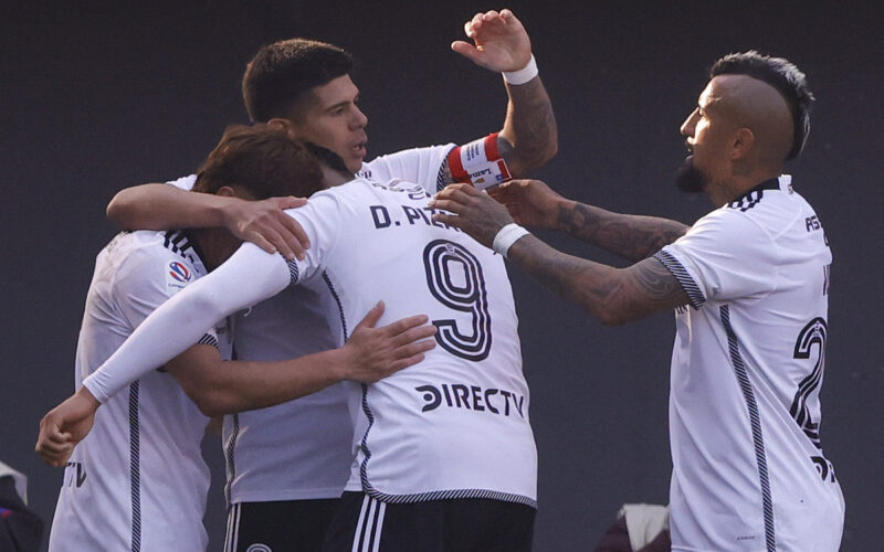 Jugadores de Colo-Colo abrazados celebrando un gol.