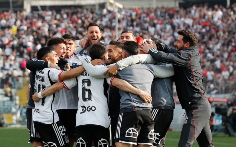 Plantel de Colo-Colo abrazado celebrando un gol en el Estadio Monumental.