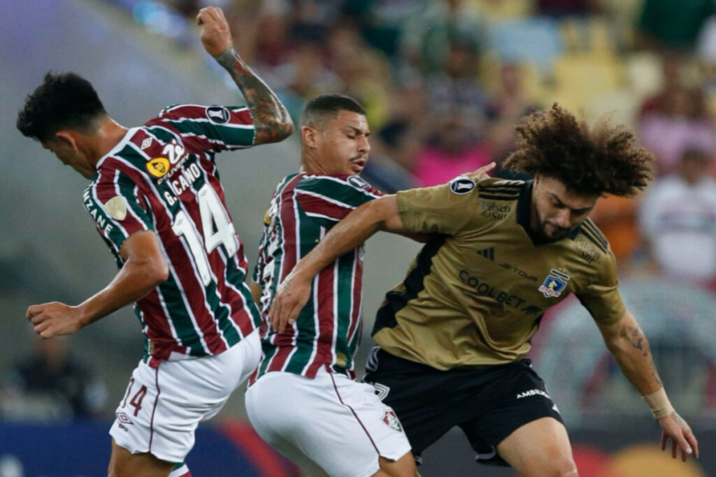 Maximiliano Falcón disputando el balón con jugadores de Fluminense en el duelo por Copa Libertadores.