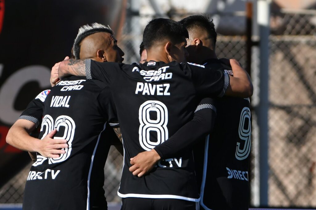 Plantel de Colo-Colo celebrando un gol con camiseta negra en el Estadio El Cobre de El Salvador.