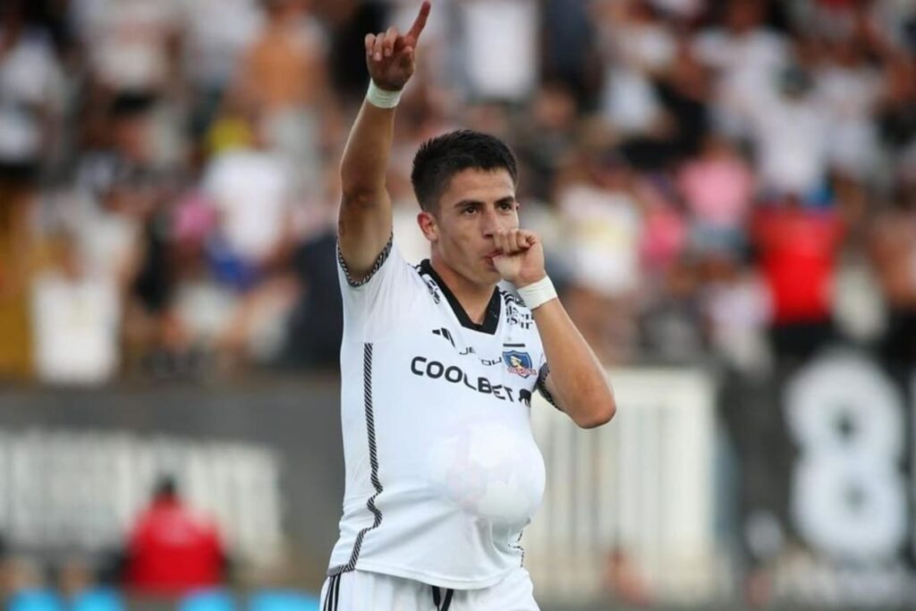 Primer plano a Matías Moya celebrando un gol con un balón dentro de su camiseta de Colo-Colo