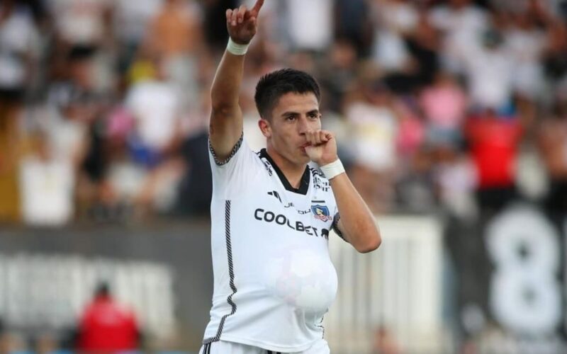 Primer plano a Matías Moya celebrando un gol con un balón dentro de su camiseta de Colo-Colo