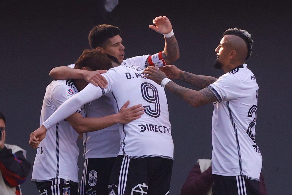 Jugadores de Colo-Colo celebrando abrazados un gol contra Audax Italiano.