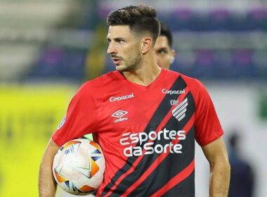 Primer plano de Lucas Di Yorio con la camiseta de Athletico Paranaense y un balón bajo su brazo.