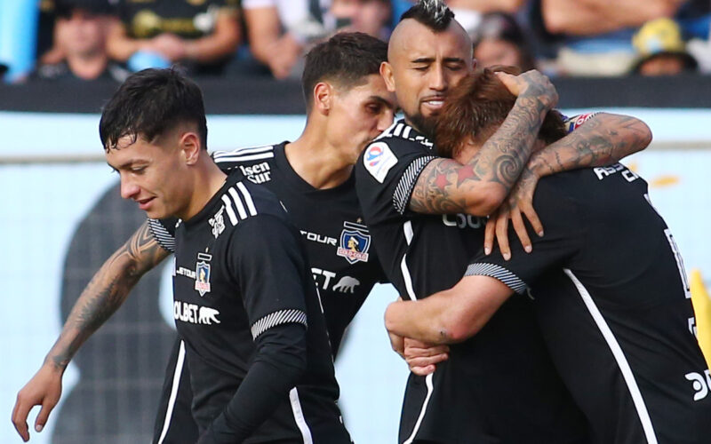 Jugadores de Colo-Colo abrazados celebrando un gol.