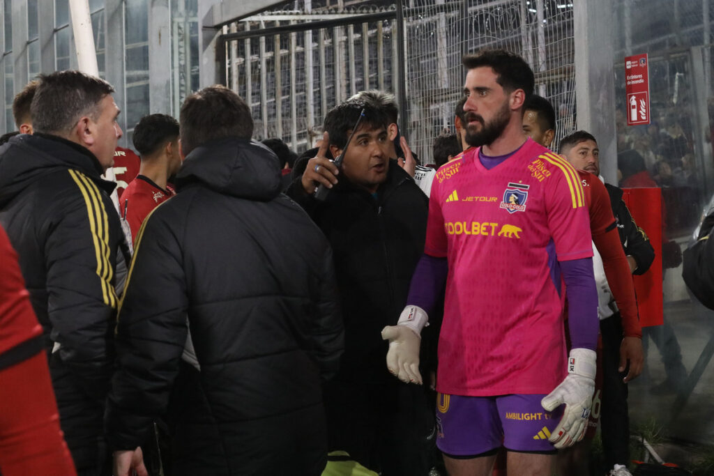 Jugadores y funcionarios de Colo-Colo sobre la cancha del Estadio Monumental tras incidentes en las tribunas.