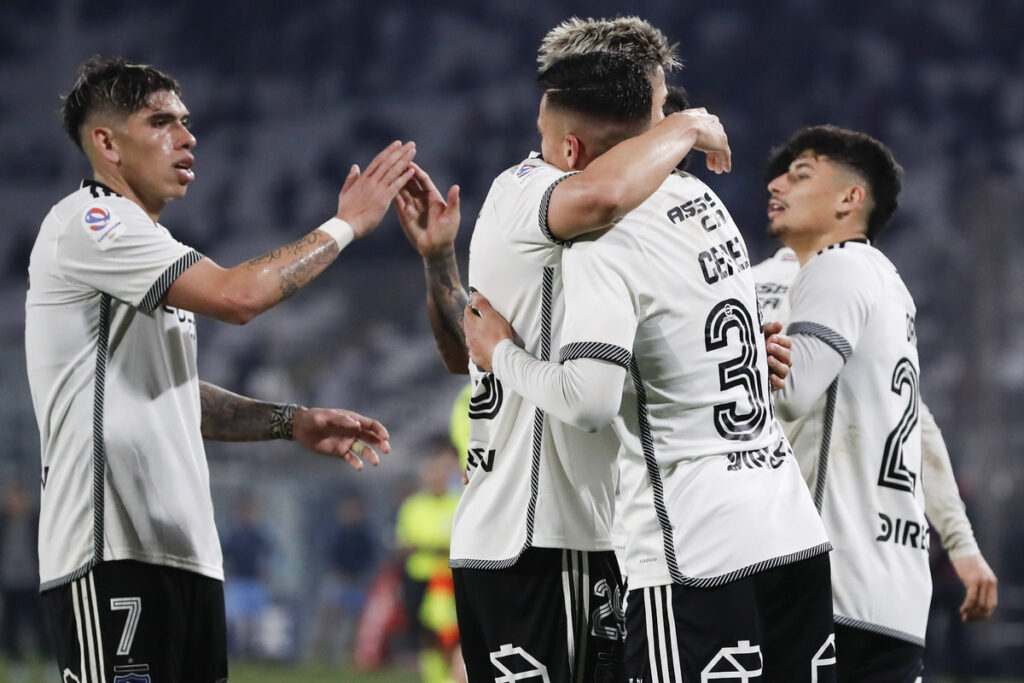 Jugadores de Colo-Colo abrazados celebrando un gol.