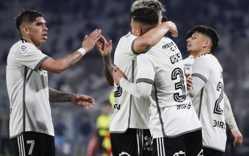 Jugadores de Colo-Colo abrazados celebrando un gol.