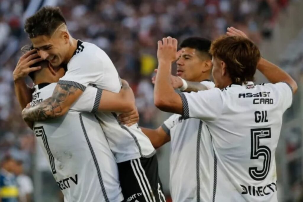 Jugadores de Colo-Colo celebrando abrazados un gol en el Estadio Monumental.