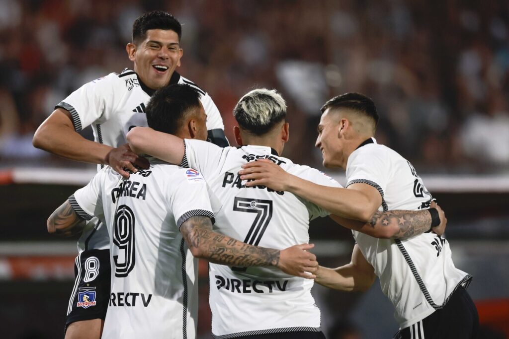 Jugadores de Colo-Colo abrazados celebrando un gol.