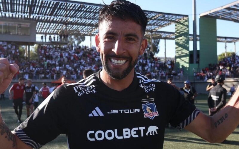 Mauricio Isla con la camiseta de Colo-Colo y los brazos en alto.