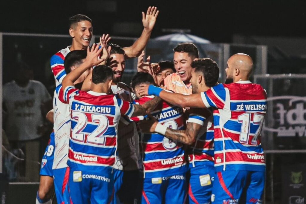 Jugadores de Fortaleza abrazados celebrando un gol.