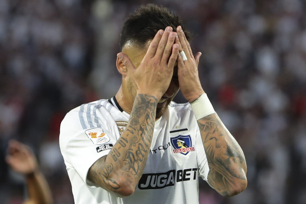 Javier Correa tapándose la cara durante un partido de Colo-Colo.