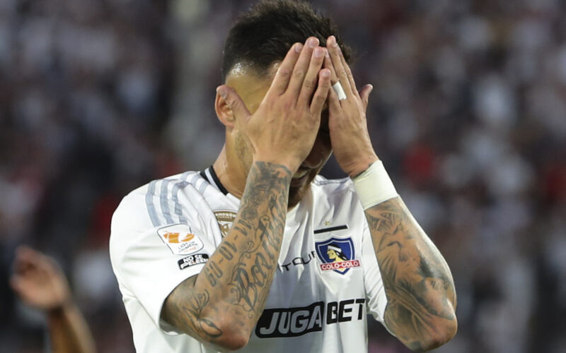 Javier Correa tapándose la cara durante un partido de Colo-Colo.