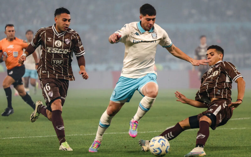 Jugador de Racing Club frente a dos futbolistas de Platense por los octavos de final del Torneo de Apertura Argentino.