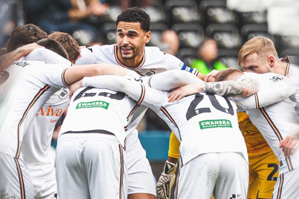 Jugadores del Swansea City reunidos con hinchas del club inglés de fondo.